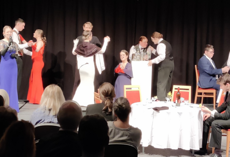 An action shot of students in the Agatha Christie rehearsals on stage with an audience at Ludlow College