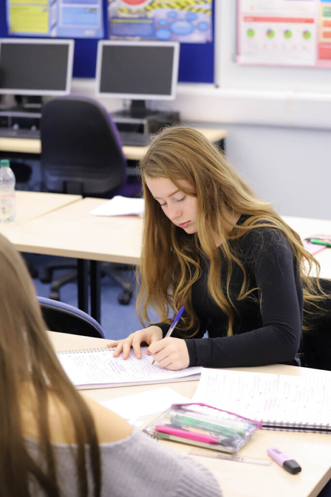 A female student writes in a workbook in a classroom at the HLNSC Ludlow College.