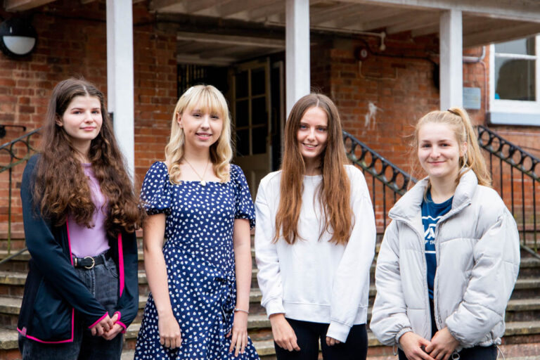 Four female students pose for a photo outside one of the buildings at the HLNSC Ludlow College.