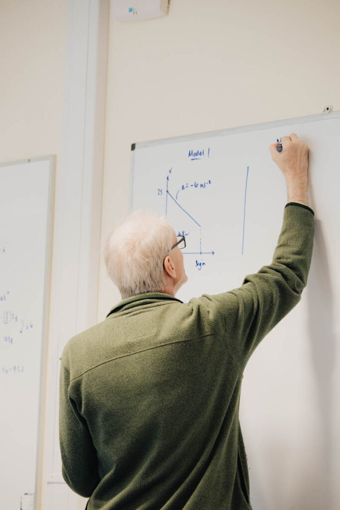 A male teacher writing on a whiteboard at Ludlow College