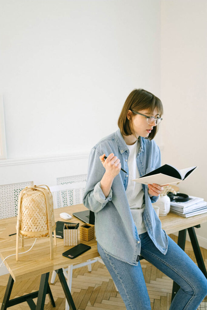 A female leaning on a desk reading a book at Ludlow College