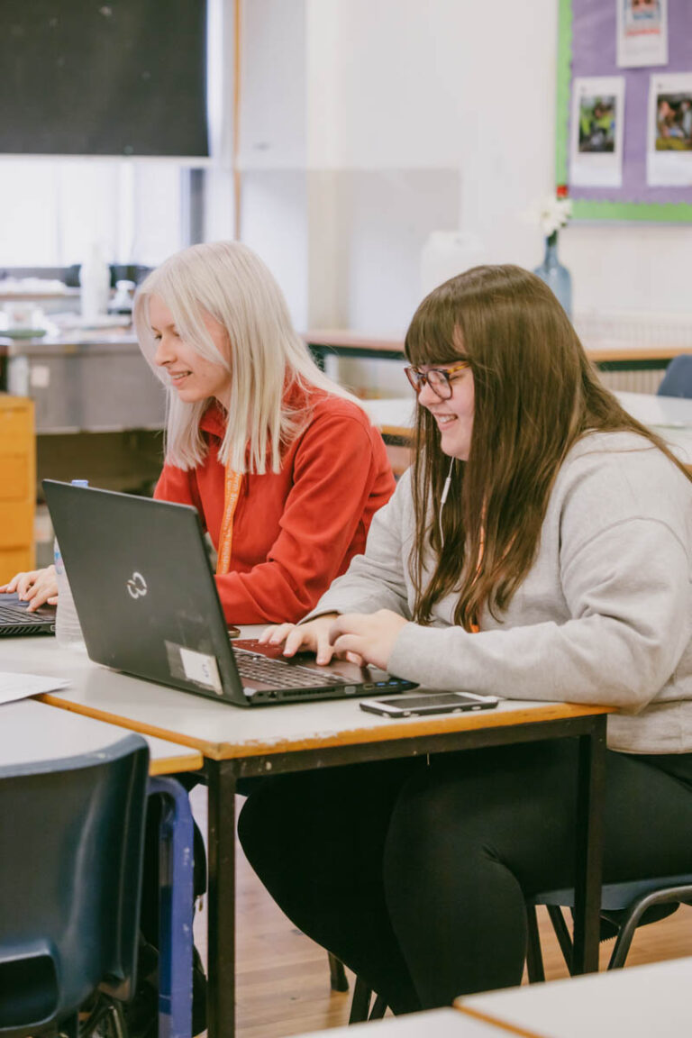 Two female students working on laptops in a classroom at the HLNSC North Shropshire College.