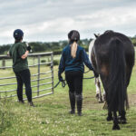 A female teacher instructing and a female students walking the horses at Walford College