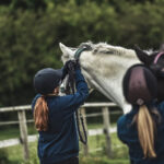 Two female students fastening the horses reins at Walford College