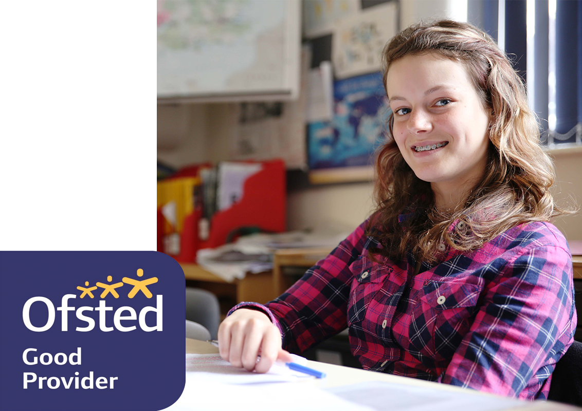 A female student smiling in a classroom with an Ofsted Good Provider logo, on a transparent background
