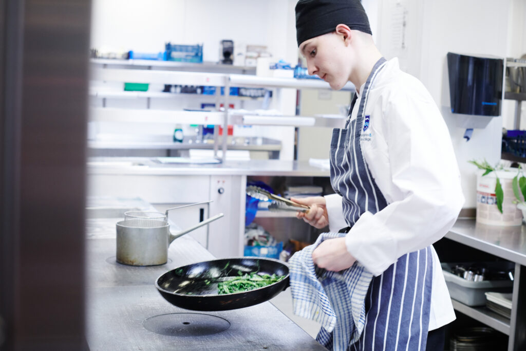 student frying food in a catering kitchen