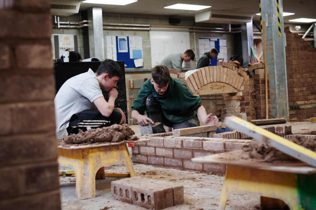 Two boys learning bricklaying and how it is done properly