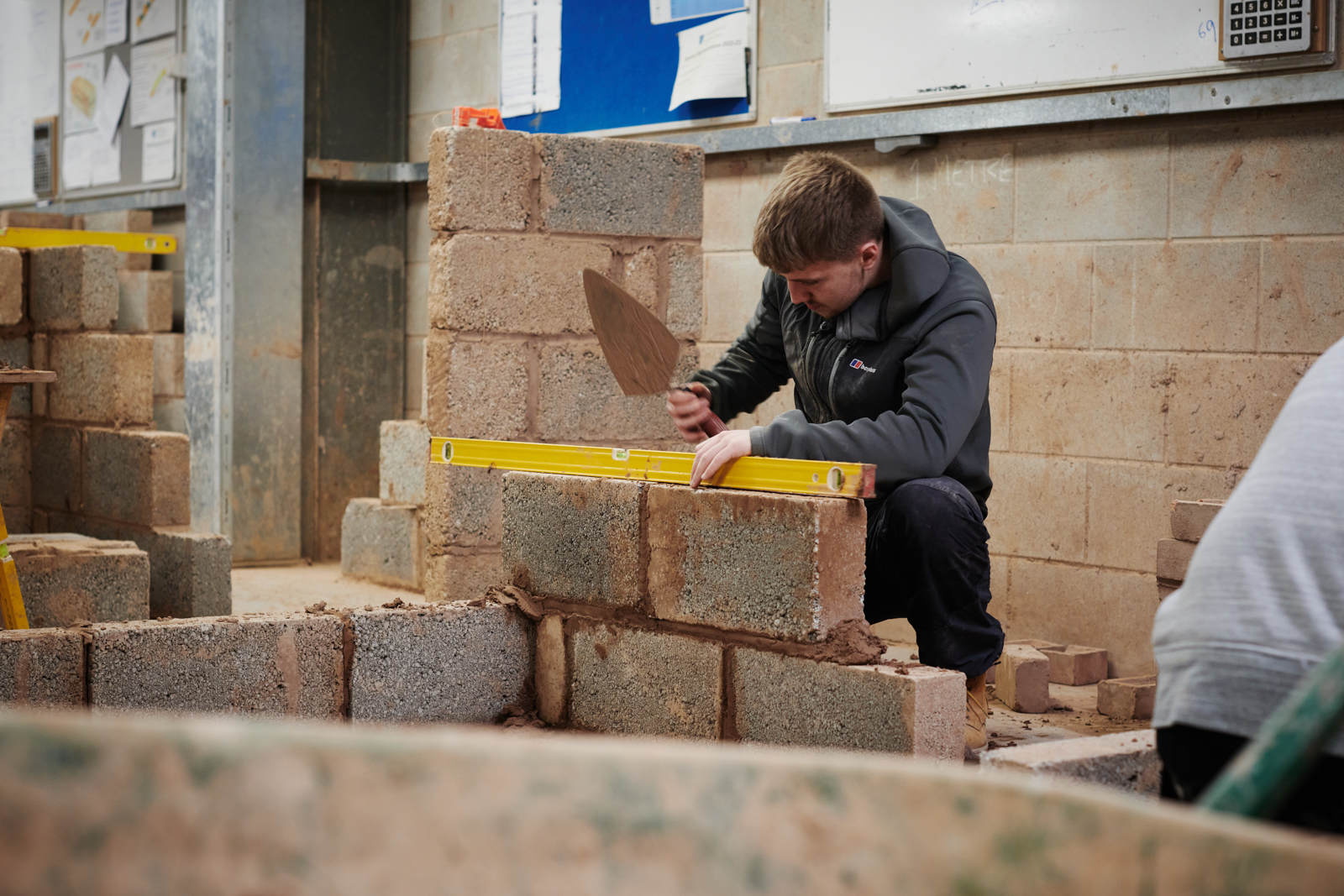 student measuring the level of the brick he has layed