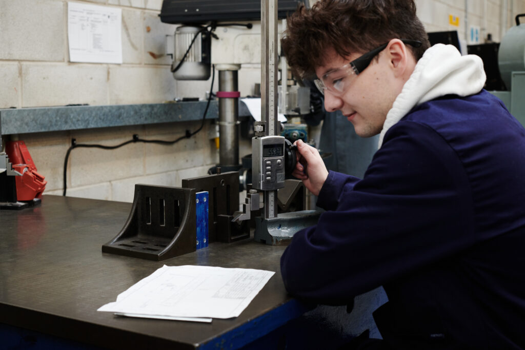 student using instructions to work on a tool in the engineering workshop
