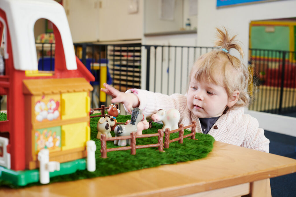 a young girl in the nursery playing with toy farm animals inside the nursey