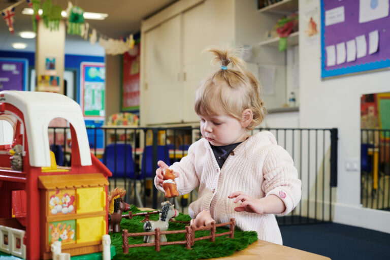 a young girl in the nursery playing with toy farm animals inside the nursery
