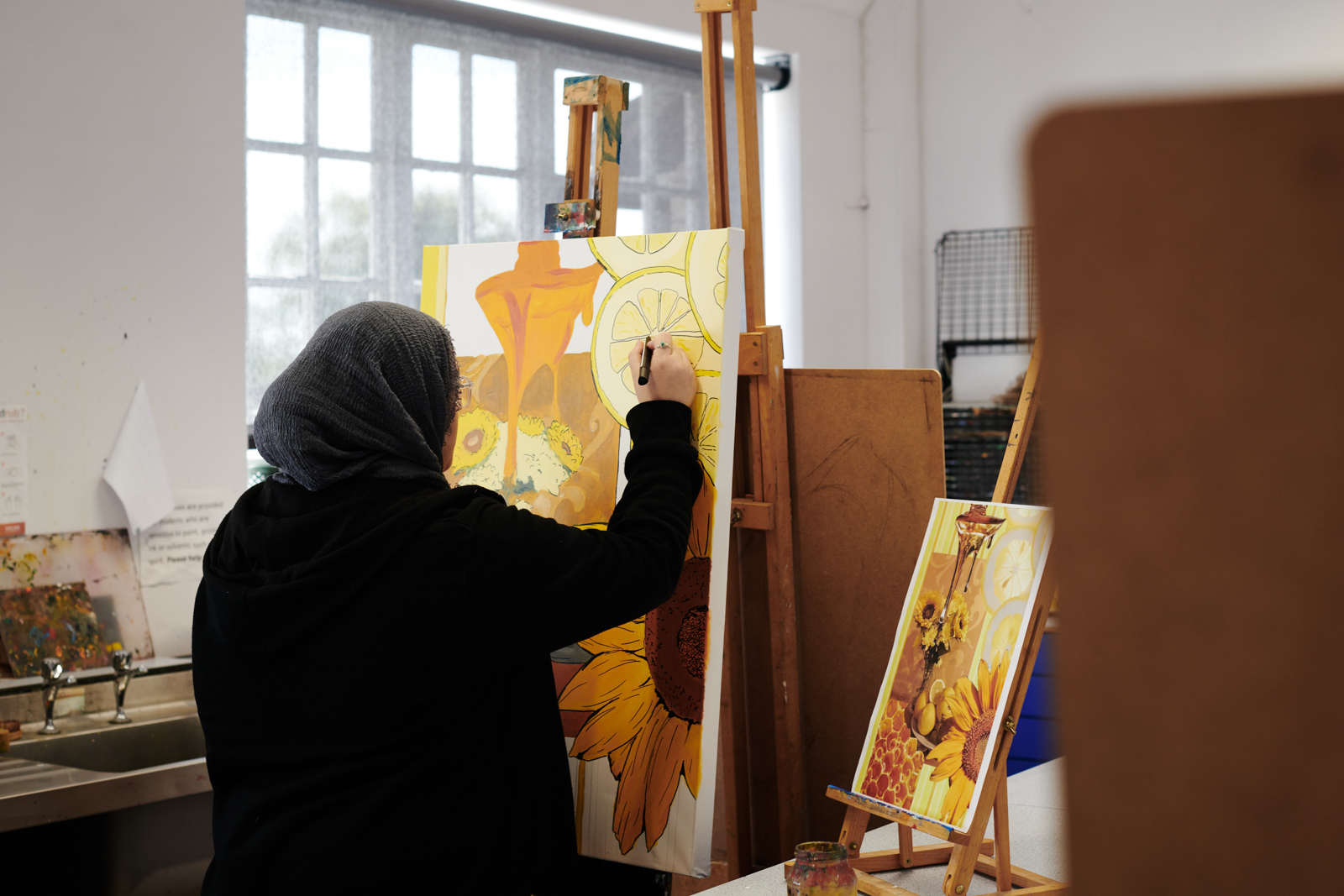 A female student painting on a easel in Art class at Ludlow College