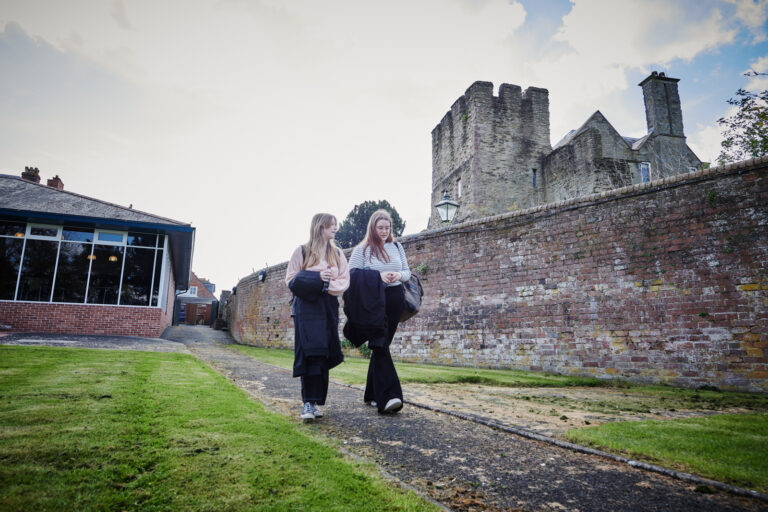 Two female students walking along a path outside Ludlow College
