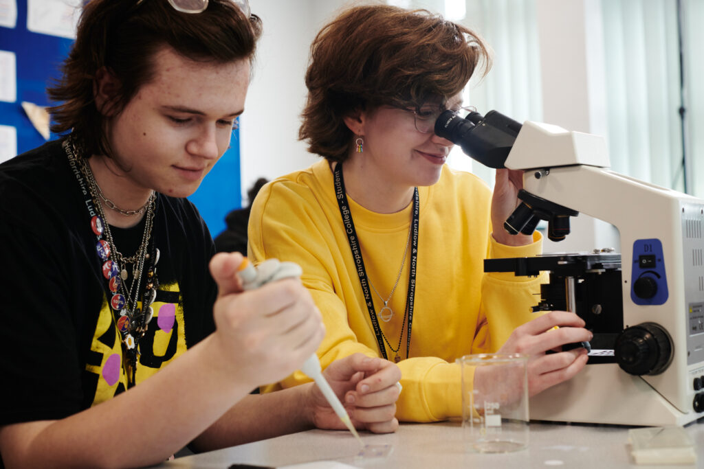 Two students using a pipette and a microscope in a Biology class at North Shropshire College