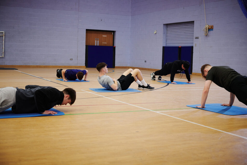 students doing press ups and sits ups in the gym
