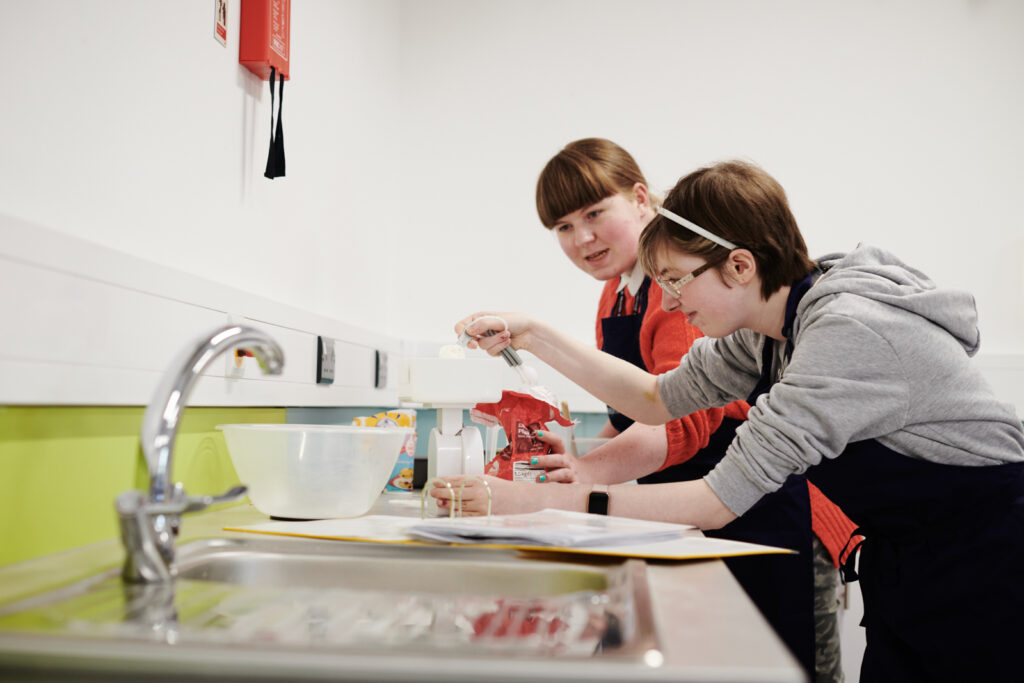 two students measuring ingredients in their accommodation kitchen