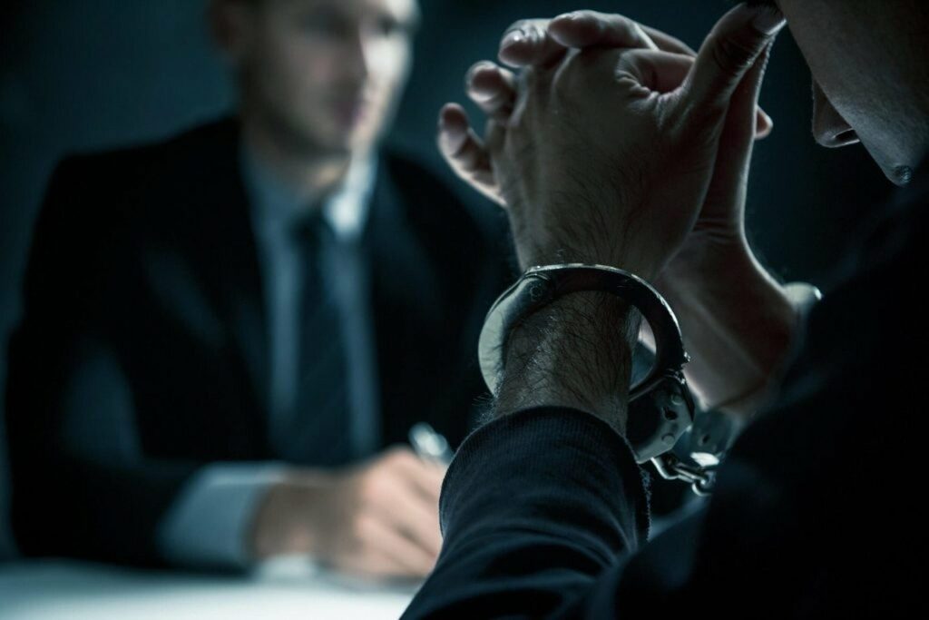 A person in handcuffs in an interview room