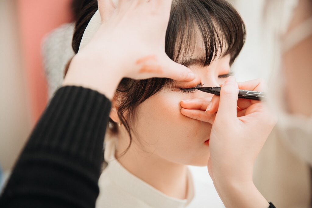 makeup artist applying eyeliner to lady