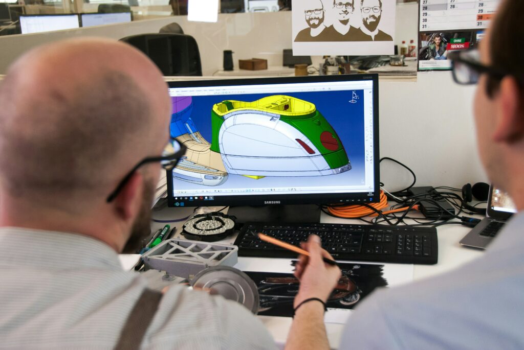 Two men looking at computer screen using CAD to design