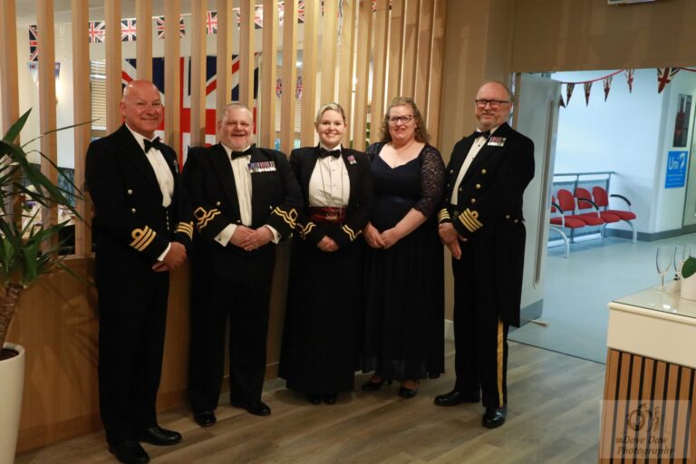 Adults pose in military dress at the VE Day celebratory meal
